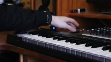 Ses mühendisi el karıştırma tahtası ve soundboard üzerinde tonobs dönüm ederken karıştırma ve ev kayıt stüdyosunda müzik parça mastering. Midi elektronik piyano klavyesi ve arka planda ses dişli ekipmanları. Ev müzik stüdyosu.