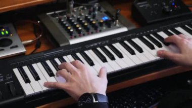 Hands midi elektronik piyano çalarken pop rock hit şarkı besteleme sırasında ev kayıt müzik stüdyosunda karıştırma tahtası ve soundboard ile. Profesyonel müzik bestecisi evde müzik stüdyosu kayıt çalışıyor.