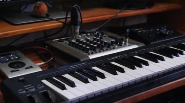 Karıştırma tahtası soundboard ve klavye ile ev müzik kayıt stüdyo çalışma alanı. Ses mühendisi ses mikserinde düğümleri döndürdü. Müzik kayıt konsepti.