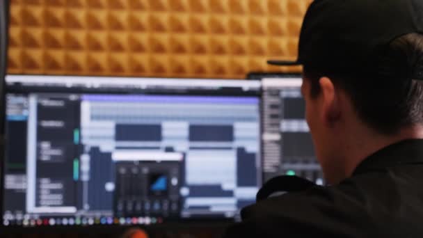 Der Toningenieur im heimischen Aufnahmestudio schaut auf den Bildschirm mit digitalem Audio-Arbeitsplatz, während er Poprock-Musik für ein Projekt mixt und mastert. junger Musikproduzent kreiert Klänge im Studio. — Stockvideo
