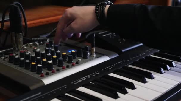 Sound engineer mixing and mastering a song on mixer board. Home studio portable mixing board. Hands turning knobs on sound mix panel and midi piano keyboard. Recording music studio. — Stock Video