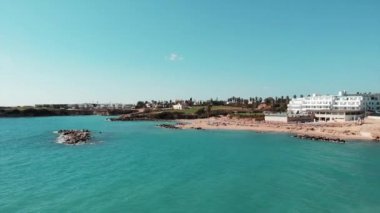 Coral Bay Kıbrıs sıcak güneşli bir günde otel ve kumlu plaj ve mavi su ile hava çekim. Sandy beach drone güneş zevk ve güneşlenme elde insanlar ile vurdu. Baf kıbrıs