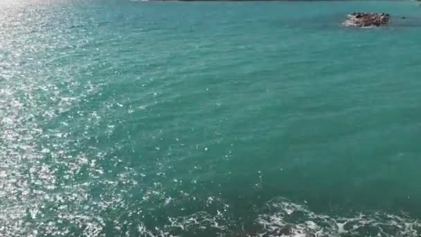 Vrouw in rode jurk genieten van zon en warme wind staan op rotsen op zee Pier met armen uit elkaar. Luchtfoto van de vrouw in rode outfit op een klif met rotsen met handen in de lucht. — Stockvideo