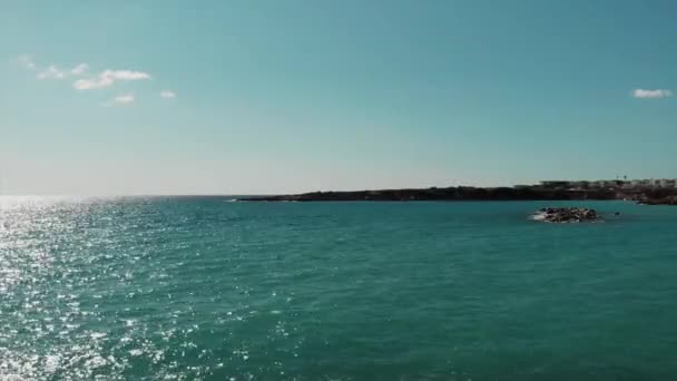 Mer Méditerranée bleue et ciel avec route ensoleillée et péninsule rocheuse à Chypre Coral Beach. Vue par drone de la mer bleue et du ciel avec reflet du soleil . — Video