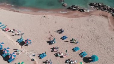 Şemsiye ve şezlong ile turistik kumlu plaj. Sahilde oynayan bir aile. Akdeniz kıyı şeridinin havadan görünümü. Plaj cenneti. Güzel kumlu plaj. İnsanlar sahilde dinleniyor. Sahilde tatil