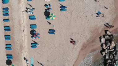 Drone şemsiye ve şezlong ile plaj boyunca uçar. Kumlu plajın havadan görünümü. Kıyı şeridinde gökyüzünden güzel bir manzara. Turistler ile tropikal egzotik plaj Havadan üst ten video