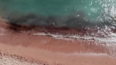 Kumlu plajın havadan üst görünümü. Mavi kristal berraklığında su. Drone güzel plaj üzerinden uçar. Okyanus dalgaları köpük yaratıyor. Mavi deniz dalgalarıdrone üst görünümü. Kumlu sahil. Coral Bay Kıbrıs