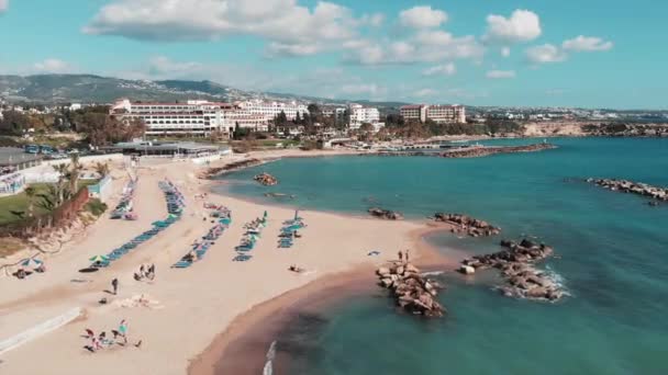 Letecký pohled na písečnou pláž. Drone, záběr turistické pláže. Drone létá pobřežím s modrou mořskou vodou. Turistická oblast s hotely a plážemi. Turisté ležící na pláži. Ženy a muži slunění — Stock video