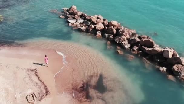Young girl walking on sandy beach. Attractive woman in red dress on beach. Aerial view of beautiful beach with clear water. Girl standing on sandy beach — Stock Video