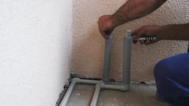 İşçi elleri pvc kaplama ile su boruları kapsamaktadır. İşçi kaplama su tüpleri ve keser kaplama. Inşaat.