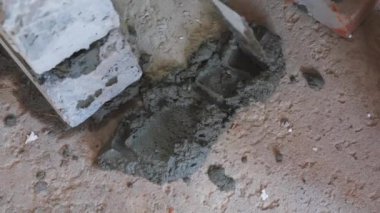 İnşaatçı çimento koyar. Çimentoyla çalış. Beton çimento harcı ile mala. Ev inşaatı. Mala ile el. Tuğla döşeme