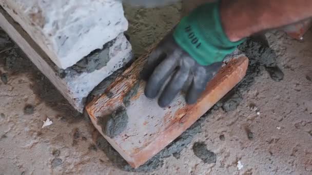 Mano de trabajador colocando ladrillo sobre cemento. Construcción de la pared. Proceso de albañilería. De cerca. — Vídeo de stock