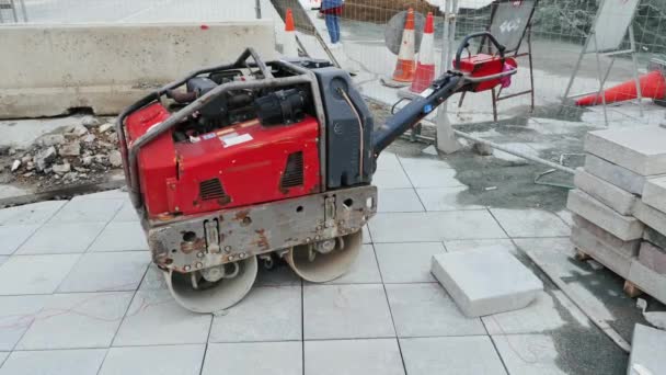 Road roller på sluten gata under rekonstruktion. Röd liten vägrulle nära väg barriärer och staket. Gatan under rekonstruktion. — Stockvideo