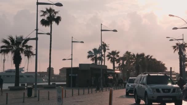 Marzo, 16, 2019 / Chipre, muelle de Paphos con puerto deportivo en tiempo lluvioso. Paseo marítimo con turistas y coches. Gente caminando por la zona turística de Paphos — Vídeos de Stock