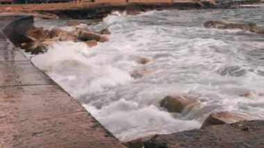 Gezinti nin yakından görünümü. Dalgaların ve taşların yakından bak. Kötü fırtınalı havalarda deniz gezintisi. Dalgalar şehir şeridine çarparak. Deniz kıyısının yakın görünümü