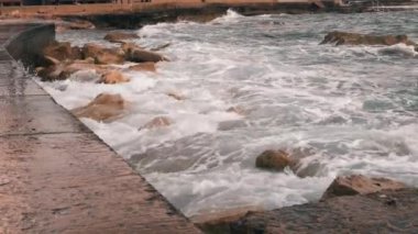 Gezinti nin yakından görünümü. Dalgaların ve taşların yakından bak. Kötü fırtınalı havalarda deniz gezintisi. Dalgalar şehir şeridine çarparak. Deniz kıyısının yakın görünümü. Yavaş çekim