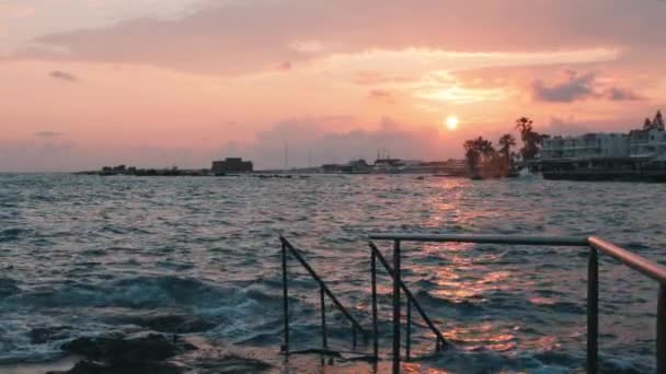 Pink sunset. Beautiful sunset. Sunset on pier. Incredible pink sunset rays. Castle on sunset. Ruins of castle on sunset. Marina on sunset. Sunset on rocky beach. Big ocean waves on sunset. Slow motion — Stock Video