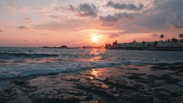 Zee golven op zonsondergang. Zeeschuim bij zonsondergang. Mooie roze hemel op zonsondergang. Roze wolken. Zonsondergang op het strand. Zonsondergang op de pier. Zonsondergang op de Middellandse Zee. Zonsondergang op zee. Toeristische promenade op zonsondergang — Stockvideo