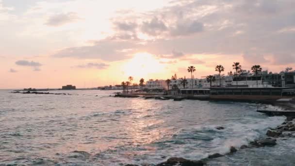 Puesta de sol rosa en la playa. Hermosa puesta de sol en el paseo marítimo. Puesta de sol rosa con el océano tormentoso en el horizonte. Puesta de sol en Marina. Gente caminando en el puerto. Paseo peatonal por la playa. Hermoso atardecer con palmeras — Vídeos de Stock