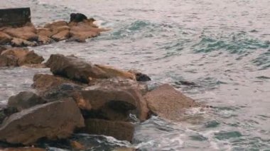 Kayalık plajın yakın görünümü. Fırtınada büyük okyanus dalgaları. Büyük kayalık taşlar okyanus dalgaları yla yıkanır. Okyanus fırtınada. Su sıçratan yakından görünümü. Kötü havalarda kayalık deniz kıyısı. Yavaş çekim