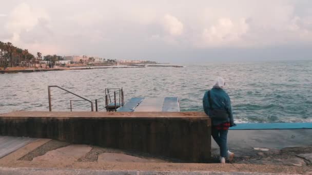 Trauriges junges Mädchen mit Blick auf stürmische See. einsame Frau am Yachthafen. Mädchen auf verlassener Promenade. junges pessimistisches Mädchen steht an der Promenade — Stockvideo