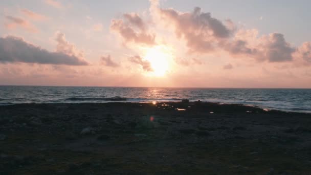 Hermosa puesta de sol rosa en la playa rocosa. Puesta de sol naranja en el mar. El sol se pone sobre el horizonte. Increíbles rayos de sol poniente. Nubes rosas contra el sol poniente. Hermoso océano al atardecer . — Vídeo de stock