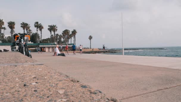 16 de marzo de 2019 / Chipre, Paphos. Hermoso paseo turístico con gente caminando a lo largo de la playa. Zona turística con cafés y tiendas de souvenirs. Corredor masculino entrenando a lo largo del muelle. Movimiento lento — Vídeos de Stock