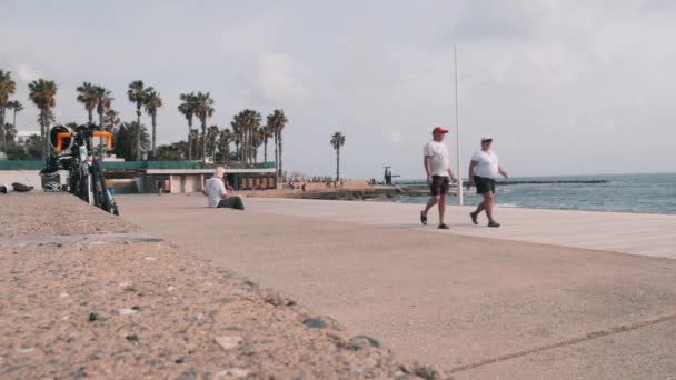 16 de marzo de 2019 / Chipre, Paphos. Hermoso paseo turístico con gente caminando a lo largo de la playa. Zona turística con cafés y tiendas de souvenirs. Corredor masculino entrenando a lo largo del muelle. Hermoso muelle con mar tormentoso — Vídeos de Stock