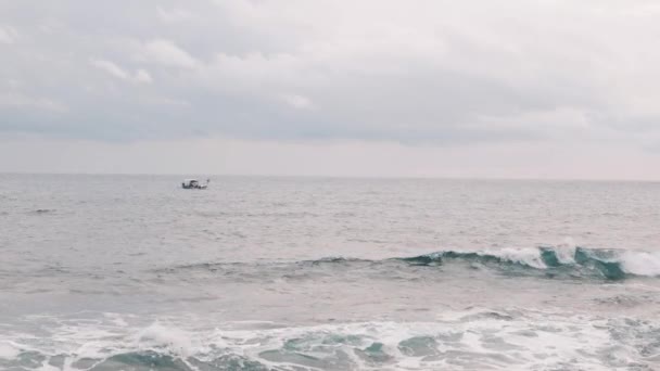 海の中の孤独な小さな漁船。古い漁師が海を航海する。男は嵐の中で釣りをしている。大波に揺るくる漁船。小さなボートが海に揺れる。スローモーション — ストック動画