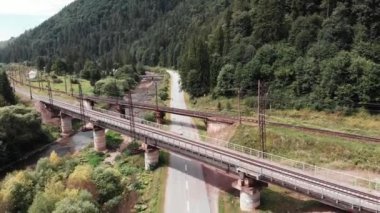 Kuş bakışı eski beton demiryolu köprüsü. İki demiryolu nun yakınında uçan drone eski köprüler. Tren köprülerinde bisikletle bisiklete binen kız eğitimi. Karpat dağların havadan drone görünümü