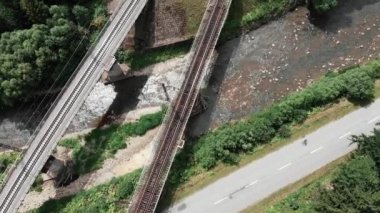 Nehirden iki demiryolu köprüsü geçti. Eski ve yeni beton demiryolu köprülerinin en iyi görünümü. Beton demiryolu köprülerinden bisiklete binen genç kadın atlet. Profesyonel bisikletçi bisikletle pedal çeviriyor
