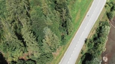 Dağlarda yol bisikletine binen profesyonel bisikletçinin havadan drone görünümü. Genç kadın triatlet eğitim kampında yarışmaya hazırlanıyor. Dağda bisiklet kadın atlet