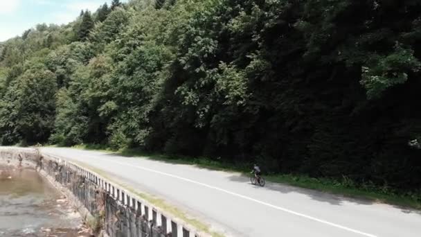 Jovem atleta se preparando para o campeonato de triatlo. Treinamento duro ciclista profissional em bicicleta antes da competição de triatlo. Menina esportiva andando de bicicleta de estrada em montanhas vista lateral drone — Vídeo de Stock