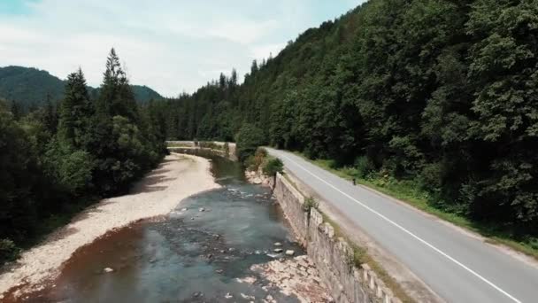 Drone volant le long de la rivière de montagne avec une belle vue. Vue incroyable sur les montagnes des Carpates. Motivé jeune triathlète à vélo seul le long de la forêt de pins. Athlète femme s'entraînant en montagne 