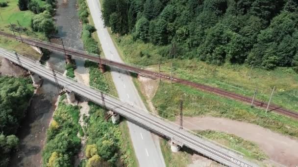 Vue aérienne par drone de deux ponts ferroviaires en béton. Vue de dessus des ponts ferroviaires traversant une petite rivière. Ponts de chemin de fer anciens et nouveaux de vue aérienne. Traversée ferroviaire à travers le paysage montagneux — Video