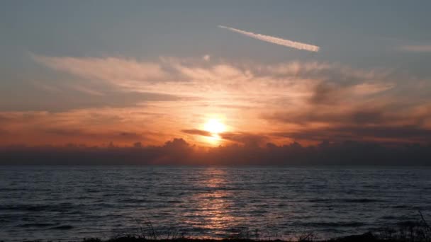 Silhouette di persone che camminano sul lungomare al tramonto. Silhouette di motociclisti che cavalcano lungo banchina al tramonto. Tramonto sul mare con cielo arancione. Silhouette di turisti che camminano su banchina — Video Stock