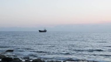 Arka planda eski paslı gemi ile Seascape. Büyük paslı gemi kayalık sahilde mahsur kaldı. Yağmurlu bir günde okyanusun güzel manzarası. Paslı kargo gemisi denizde mahsur kaldı. Kayalık kıyıya yakın kargo gemisi