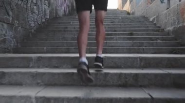 Kaslı güçlü tabaklanmış erkek bacakları merdivenlerden yukarı koşar. Sportif güçlü erkek bacaklarının arka görünümüne yakın. İnce atletik adam merdivenlerden yukarı koşar. Siyah kıyafetli profesyonel atlet merdivenlerden yukarı koşuyor. Yavaş çekim