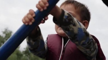 Mutlu çocuk yüzünün yakından görünümü. Parkta teknede yelken küçük sevimli çocuk portresi. Sevimli çocuk konuşuyor ve gülümsüyor. Şanslı çocuğun yüzünüyakından görmek.