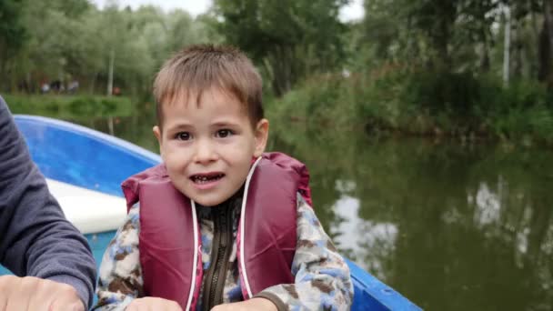 Portrait de petit enfant adorable tient la pagaie. Vue rapprochée du petit garçon mignon souriant à la caméra sur le lac. Enfant heureux tient la pagaie et parle à la caméra dans le parc .