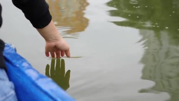 La mano de la mujer toca suavemente la superficie de agua verde en el lago. Chica feliz lentamente lleva su mano sobre el agua. El primer plano de la mano de mujer toca el agua verde. Chica lleva la mano en el agua en el lago . — Vídeos de Stock