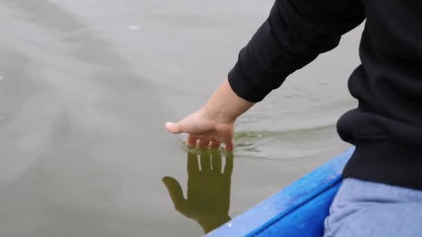 Ung flicka försiktigt röra vatten på sjön. Kvinnan leder handflatan på grönt vatten. Närbild av kvinnan hand berör vatten i parken. Kvinna hand röra vatten på sjön. — Stockvideo