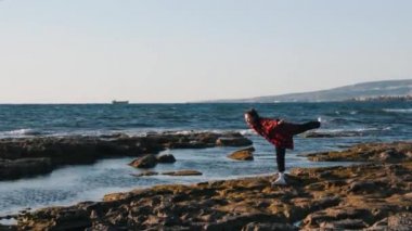 Sevimli genç hipster kadın deniz kıyısında duran ve komik pozlar yapıyor. Sahilde eğlenen mutlu gülümseyen kadın. Kırlangıç pozisyonunda duran kadın. Komik yutkunan kadın poz veriyor. Kadın sahilde eğlendi