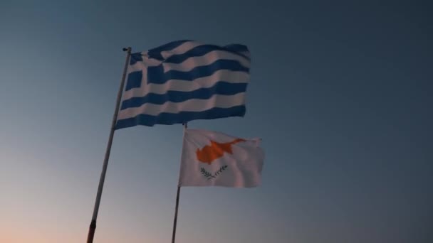 Kıbrıs ve Yunan bayrakları mavi gün batımı gökyüzüne karşı rüzgarsal sallayarak — Stok video