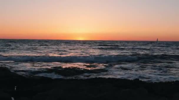 Wunderschöner Sonnenuntergang mit kleinem Schiff am Horizont. kleines Boot, das im Meer gegen den orangen Sonnenuntergang schwimmt. Unglaubliche Meereswellen bei Sonnenuntergang — Stockvideo