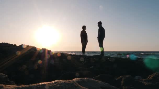 Silhouette eines niedlichen Mannes, der auf seinem Knie steht und seiner Freundin bei Sonnenuntergang einen Heiratsantrag macht. junge erstaunt glückliche Frau, die einwilligt zu heiraten, indem sie Ja zu einem Heiratsantrag sagt. Romantische Verlobung am Strand bei Sonnenuntergang — Stockvideo