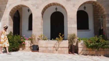 Sıcak yaz gününde eski şehir caddesinde yürüyen yaz elbisesi ve hasır şapka neşeli kadın turist