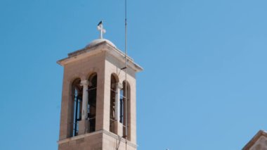 Mavi berrak gökyüzüne karşı çan kulesi ile şehir kilisesinin üst yan görünümü. Beyaz çan kulesinin yakından görünümü