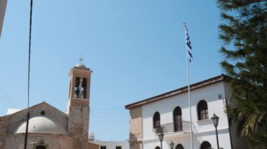 Arka planda kilise ile havada uçan yüksek bayrak direği üzerinde Yunan bayrağı güzel görünümü