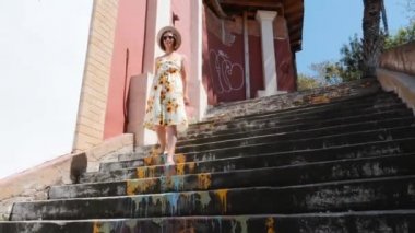 Ayçiçeği ve siyah güneş gözlüğü ile elbiseli beyaz kadın yaz tatilinde eski şehir merkezinde yürüyor
